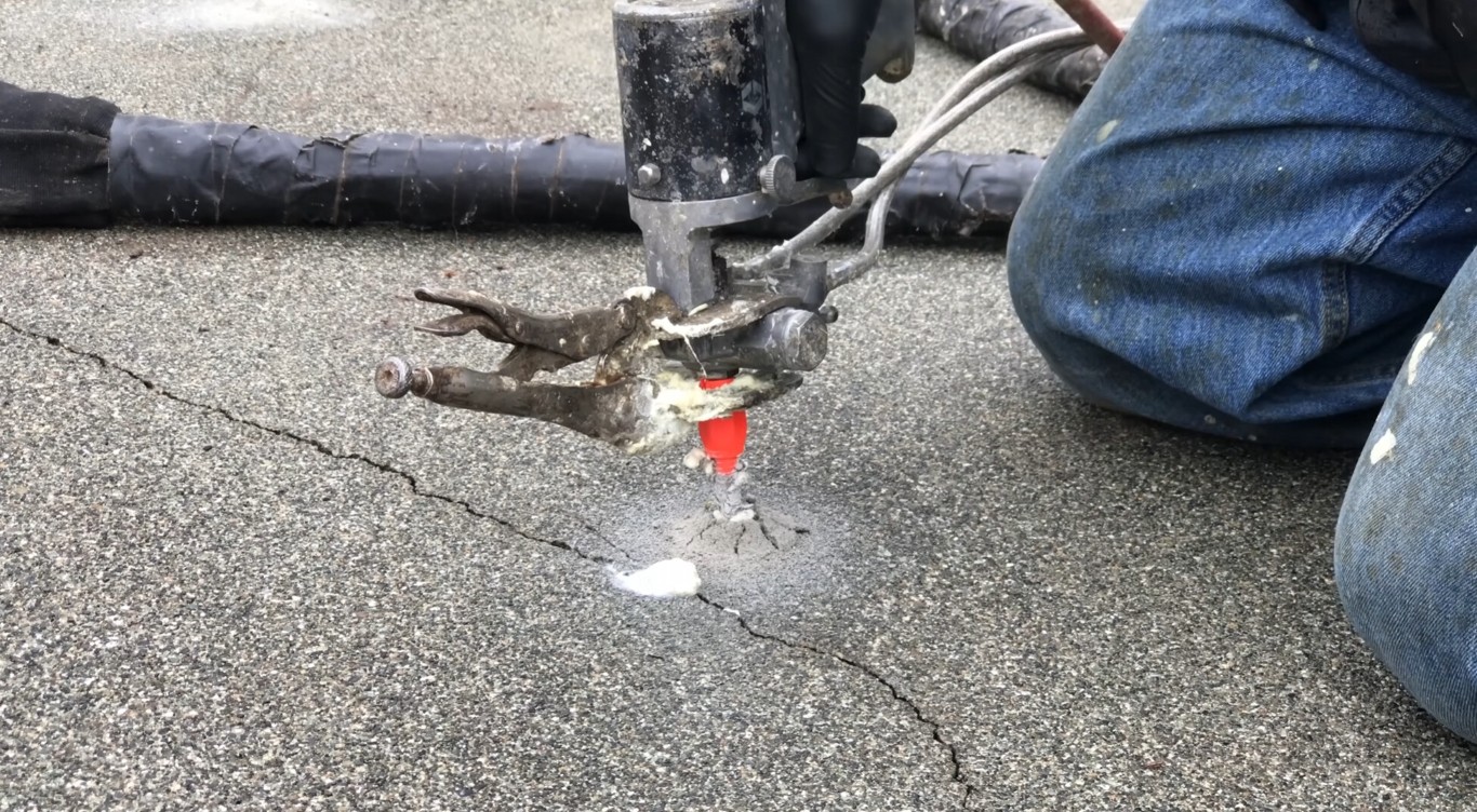 Technician performing concrete crack repair with epoxy injection on a driveway in Abilene, TX